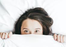 Girl in fear hiding under a blanket